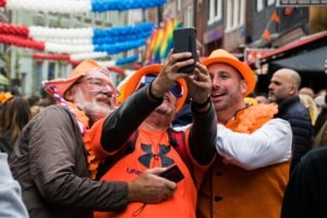 People making a selfie on the street while celebrating kingsday in Amsterdam