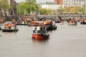 Boats on a canal during Kingsday in Amsterdam