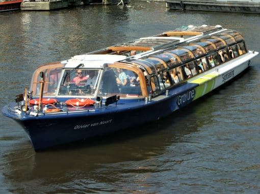 Typical Amsterdam canal boat cruising the historic canals, perfect for an authentic boat tour in Amsterdam.
