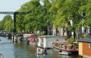 : Authentic Amsterdam canal with boats, houseboats and an industrial bridge. perfect setting for your ideal boat tour in Amsterdam.