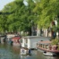 : Authentic Amsterdam canal with boats, houseboats and an industrial bridge. perfect setting for your ideal boat tour in Amsterdam.